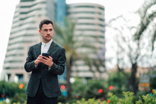 Businessman using smartphone outdoors, connecting with technology in a modern urban environment
