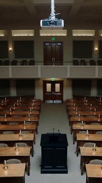Vertical video: Camera tightening to lectern with mics, keeping centered in hall, showing projector