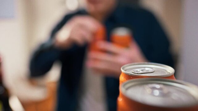 Idea of chilled refreshment rows of silver metal cans of carbonated drinks sit on bright refrigerator shelf under cool white light, while man reaches in to pull a cold can from the organized lineup