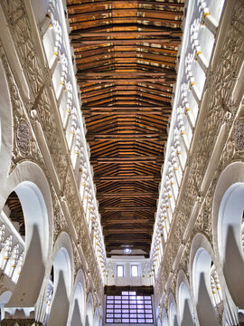 Ancient Synagogue Interior with Arches - The ornate interior of a historic synagogue features a row of elegant white octagonal columns, horseshoe arches, and intricate Moorish decor