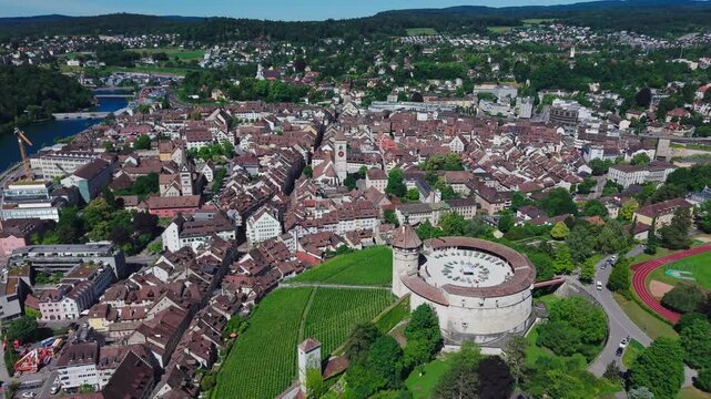 Aerial tracking view flying left and panning right over the historic Munot fortress, vineyard, and the old town cityscape of Schaffhausen.