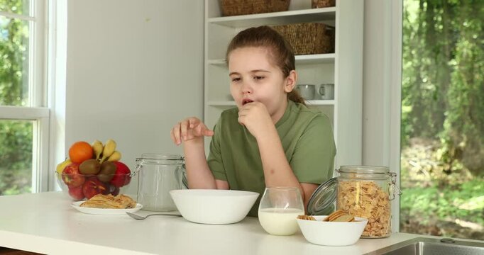 Kid with Healthy food at home. Child eating at the kitchen. Healthy eating with fruit, vegetables, and milk. Daily healthy eating habits for a kids. Child eating crackers with milk at home.