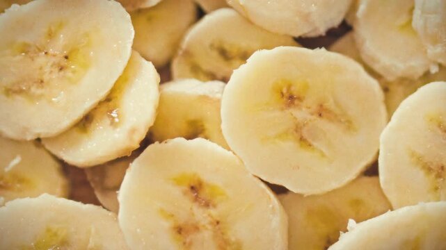 Thin yellow banana slices are delicately cut and piled irregularly, forming textured 3D stack. The composition emphasizes a diet-friendly food concept, showcasing nutritious, low-calorie snack appeal
