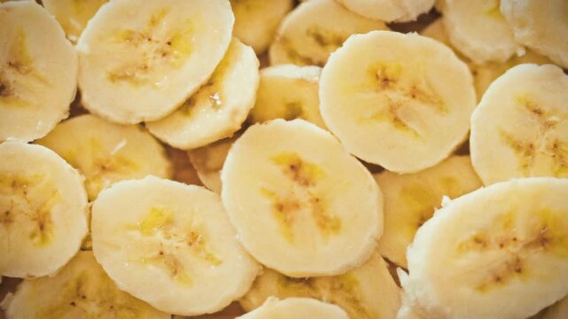 Thinly sliced ripe bananas overlap, forming a dense, vibrant yellow fruit stack. This natural arrangement embodies a healthy snack concept, showcasing the fruit's simplicity and appeal