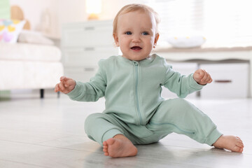 Fototapeta premium Cute little baby in onesie on floor at home