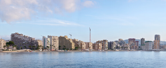 Panoramic waterfront skyline of Calpe on Spain's Costa Blanca, with Mediterranean sea, beachfront apartment buildings and calm morning light, ideal for coastal travel and destination themes. © Jacek