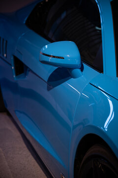 Close-up of a blue painted side mirror on a sports car.