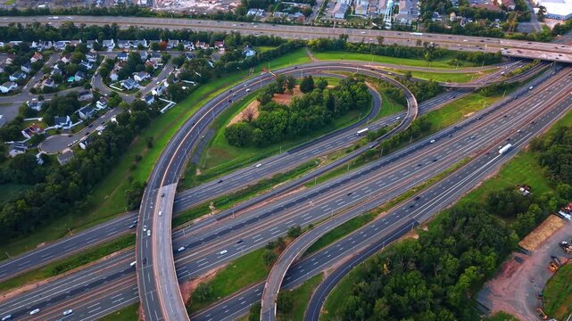 Vehicles of various colors appear tiny as they travel by the expansive, multi-lane road network. 
