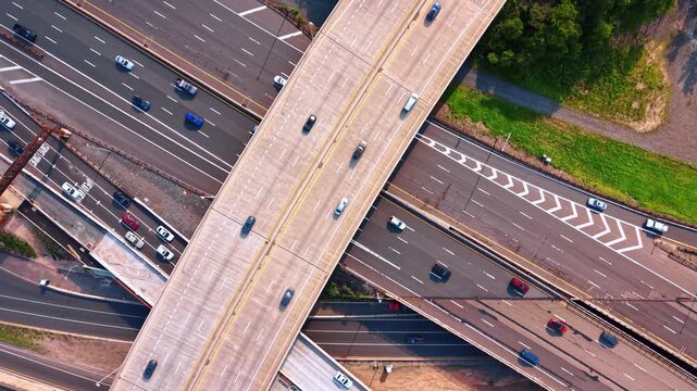 Above the multi-level highway interchange with lots of moving cars. Bustling traffic on the modern expressways in the urban infrastructure.