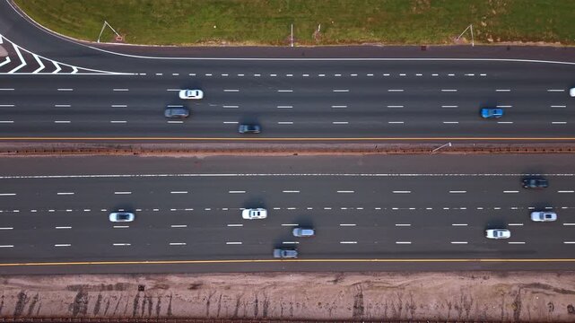 Complex network of highways showcases intricate transportation engineering from above. Several cars travel along the sweeping overpass while a wider, multi-lane interstate handles traffic below.