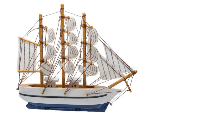 Wooden model sailboat sailing with white sails
