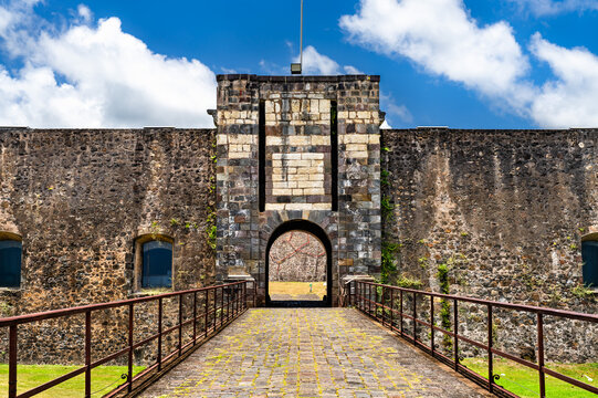 Cobblestone bridge leading to the entrance gate of historic Fort Delgres in Basse-Terre Guadeloupe under a blue sky.