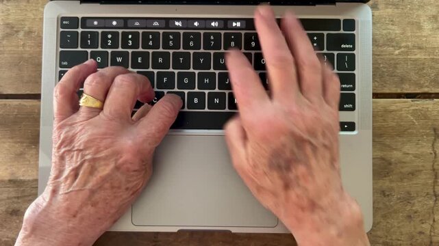 Senior person typing on laptop computer keyboard overhead view
