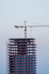 High-rise building under construction with crane against twilight sky © Two Horizons
