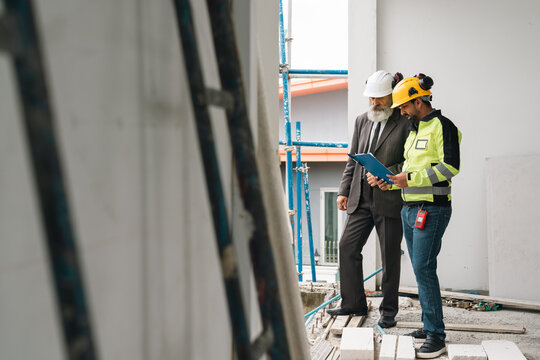 Construction worker safety engineer building inspection construction site hard hat protective clothing blueprint industrial building construction worker and safety engineer conducting building