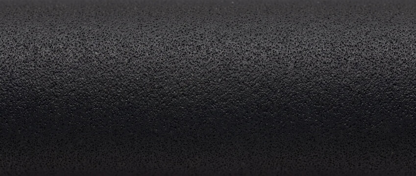 Macro of textured black ink roller surface. Porous rubber printing tool background. Close up of black foam material