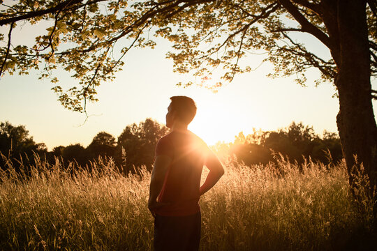Man Standing in Golden Sunset Field Reflecting on Faith, Hope and Spirituality
