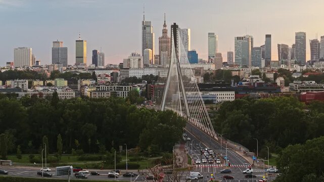 Smooth aerial panorama from left to right across Warsaw at golden hour, revealing Swietokrzyski Bridge over the Vistula River and downtown skyline with modern skyscrapers in warm evening light