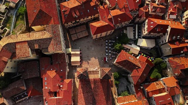 kotor, montenegro - aerial top down view of a paved old town square with market stalls, cafe awnings, colourful balloons and people walking between medieval buildings