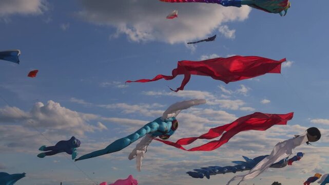 Large colorful kites filling the summer sky during an outdoor festival, evoking family recreation, freedom and playful leisure.