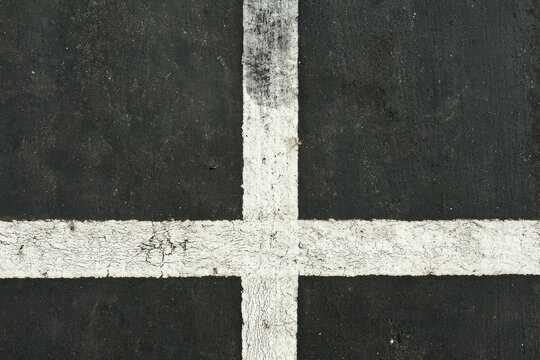Close-up of weathered white lines on a dark, textured surface