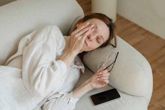 Eye Fatigue in Midlife Working Woman Resting Beside Smartphone with Glasses