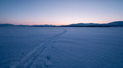 Fototapeta premium Snowy mountain landscape with ski tracks at sunset copy space