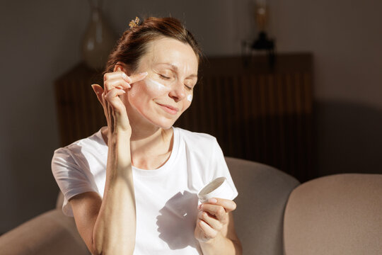 Mature Woman Applying Face Cream in Warm Morning Sunlight