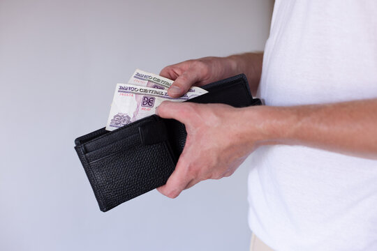  Man holding 100 Cuban peso banknote and wallet