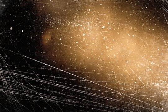 Abstract texture of dark scratched surface with warm golden light leak