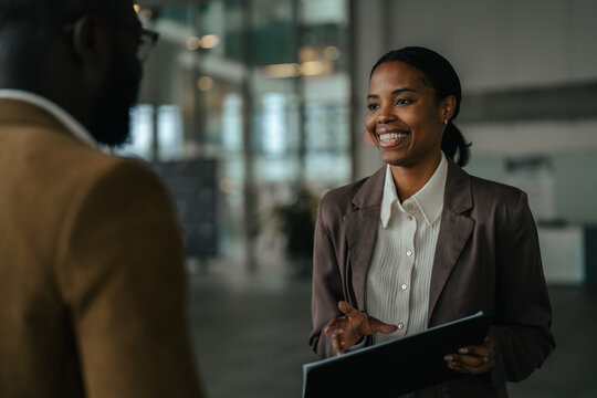 Professional black woman smiling discussing business with colleague