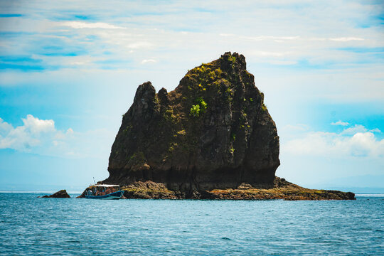 Tour Boat Near Massive Rock Formation in Tropical Ocean