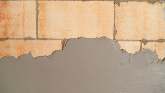 Applying fresh plaster mortar on aerated concrete block wall during construction