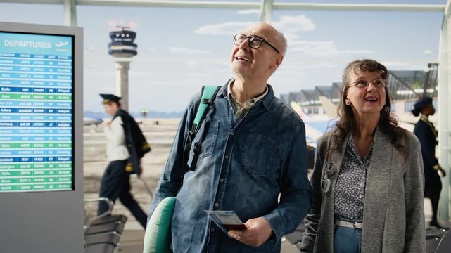 Active retirees walk through an airport terminal with luggage excited for vacation and sightseeing adventure representing freedom and challenging stereotypes about aging through independent travel.