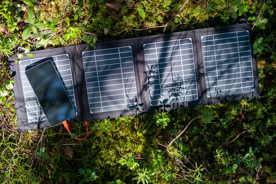 Tourist tent with solar panel and portable power station in the forest. Eco-friendly camping setup.