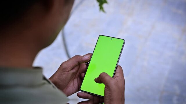 Modern smartphone with green screen chroma key display, man holding mobile device mockup for software video replacement and UI design showcase
