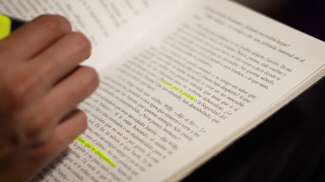 Close-up of a hand marking key text with a yellow highlighter against a soft blurred background.
