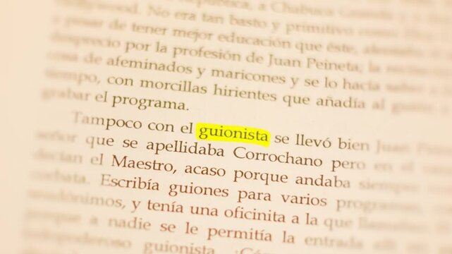 4K macro zoom-in on the Spanish word 'guionista' printed in the middle of a book page with warm cozy lighting.