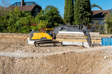 Large yellow excavator working beside foundation formwork at a residential site © FotoV