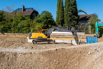Tracked excavator beside concrete foundation work on a sunny building site © FotoV