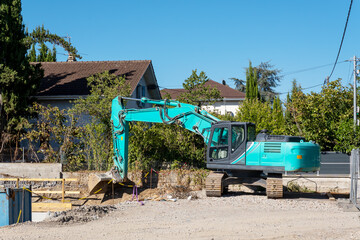 Hydraulic excavator with lowered bucket on a gravel residential worksite © FotoV