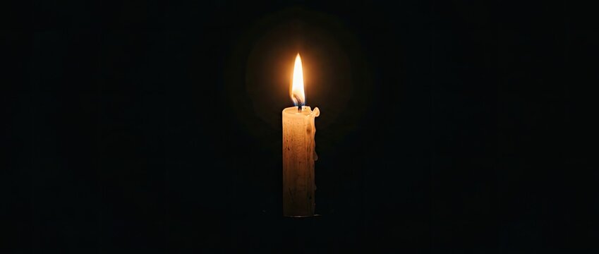 Single Lit Candle Burning Brightly In Complete Darkness