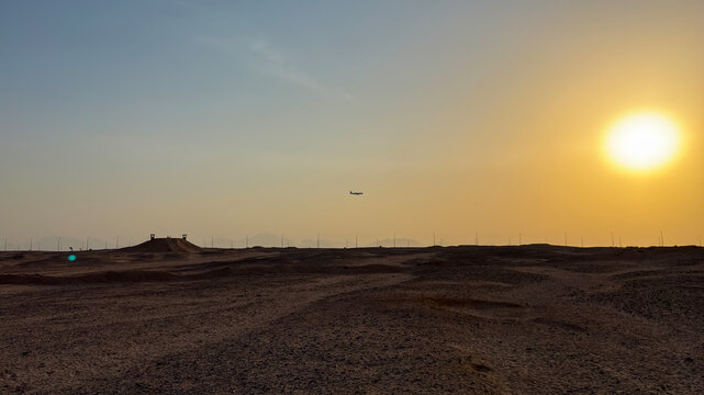 Airplane flying over vast desert landscape at sunset