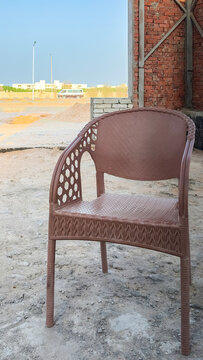 Brown plastic chair standing outdoors near a brick wall
