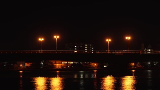 4K Horizontal time-lapse of car light trails moving across a glowing city bridge at night (Versatile 16:9 cinematic Japanese nightscape background)