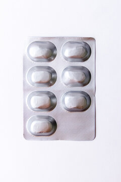 Seven white tablets sealed in a silver blister pack on a clean white background