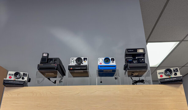 Orlando, Florida, US - September 14, 2026: Vintage Polaroid cameras on a shelf displaying various iconic models from the 1970s and 1980s. The folding cameras are One Step Flash, Impulse, and Sun600.