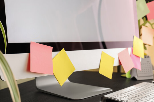 Blank sticky notes on computer monitor in office, closeup