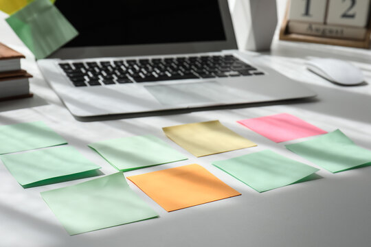Blank sticky notes with laptop on desk in office, closeup