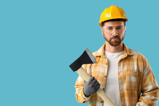 Male worker with ax on blue background